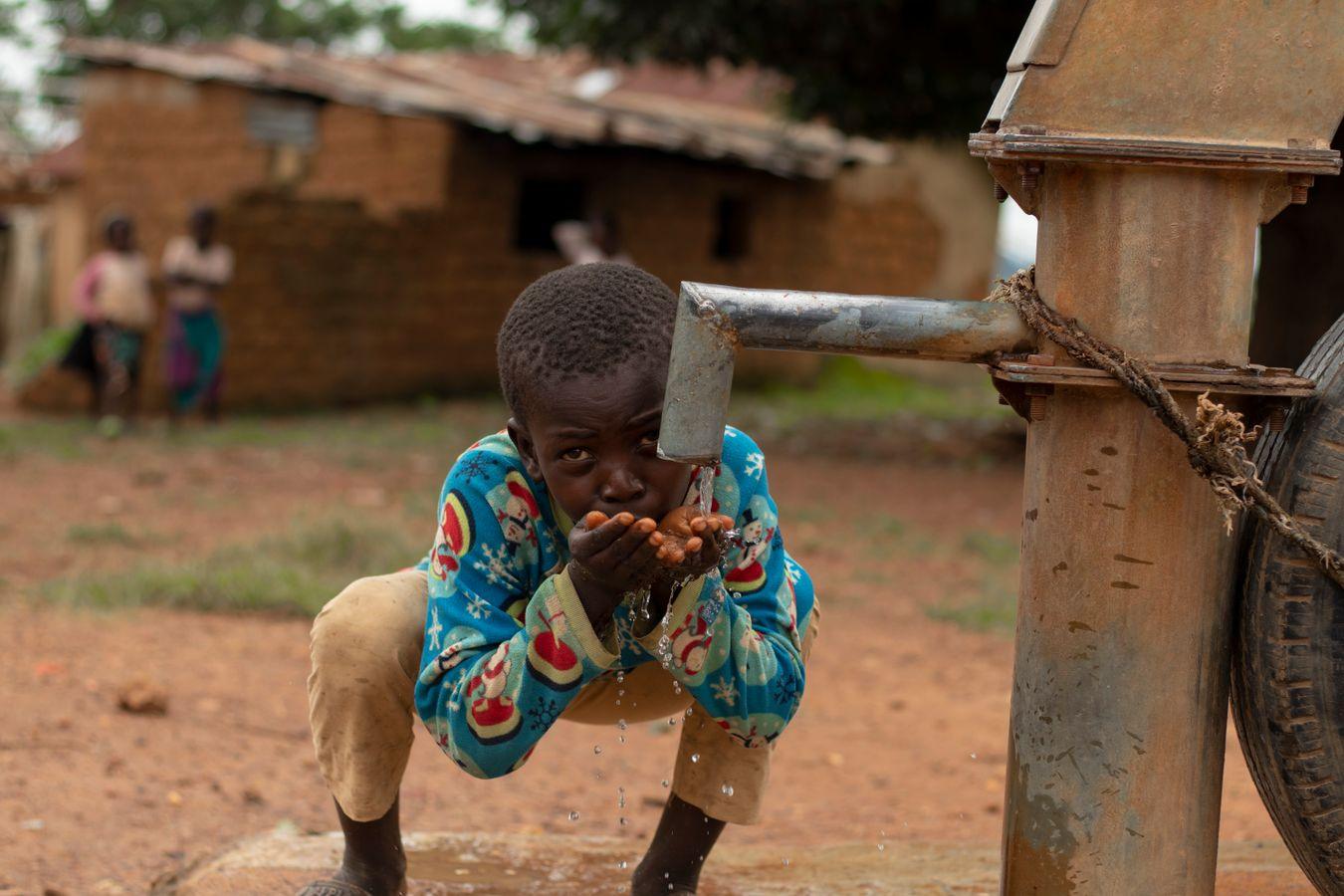 A child drinks from a village water pump