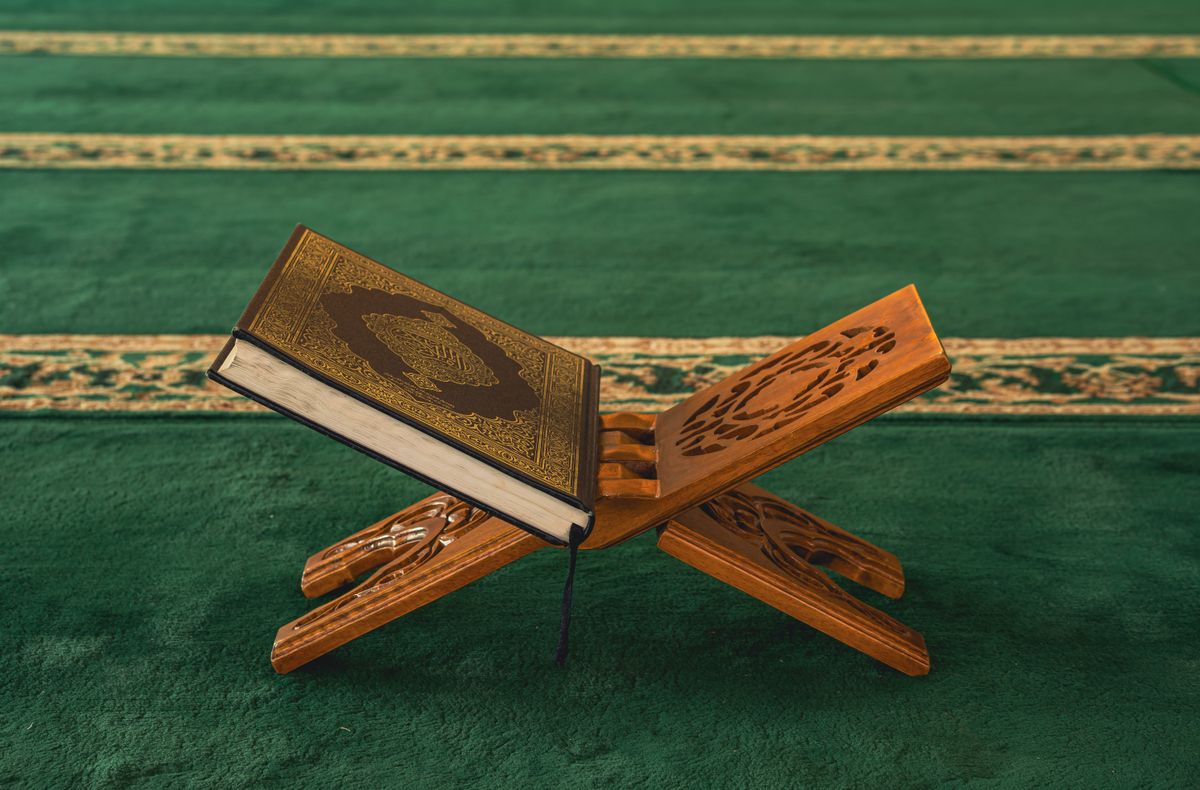 A copy of the Qur’an resting on a wooden stand in a mosque