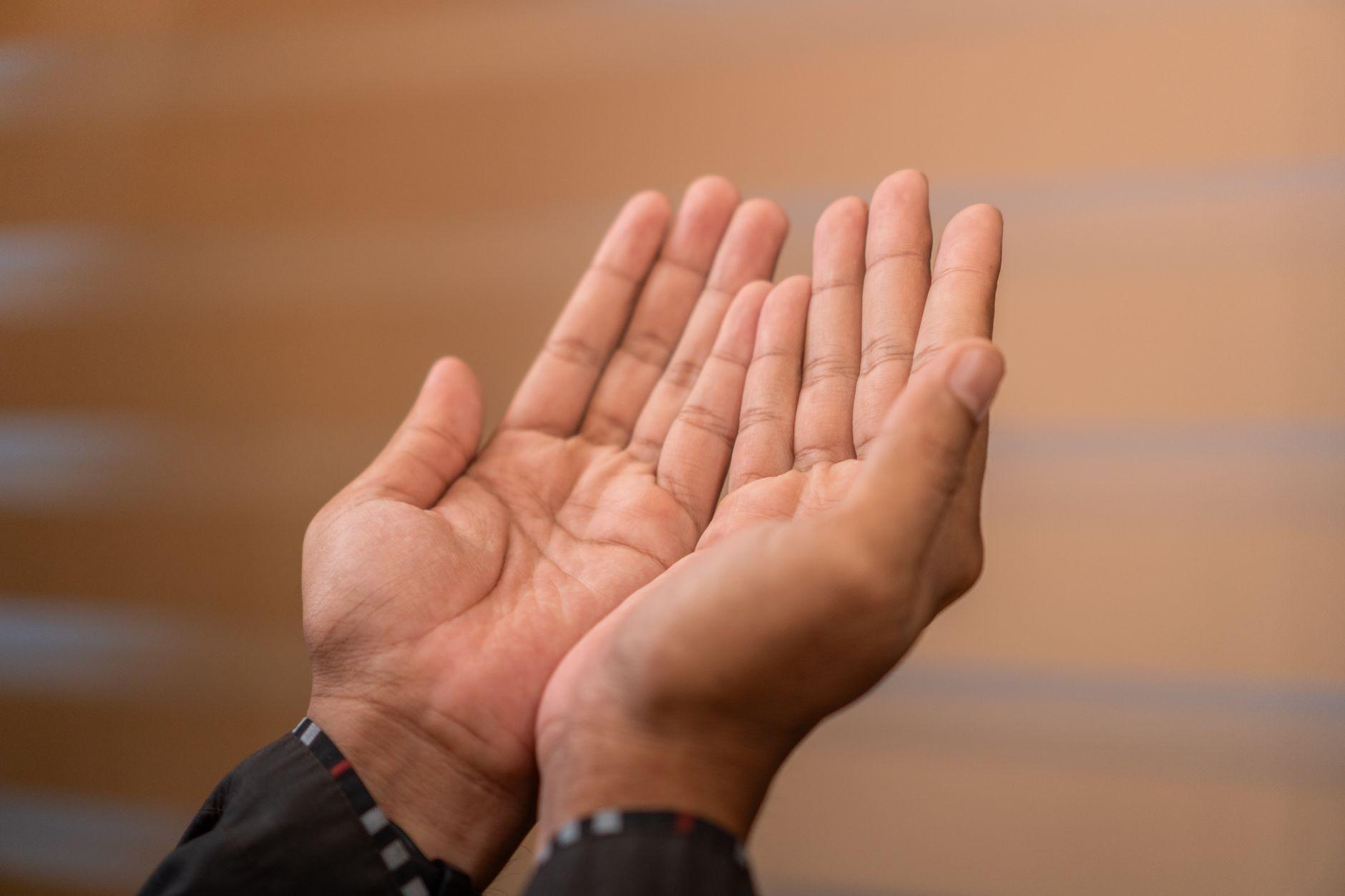 A man raises his hands in dua, palms open