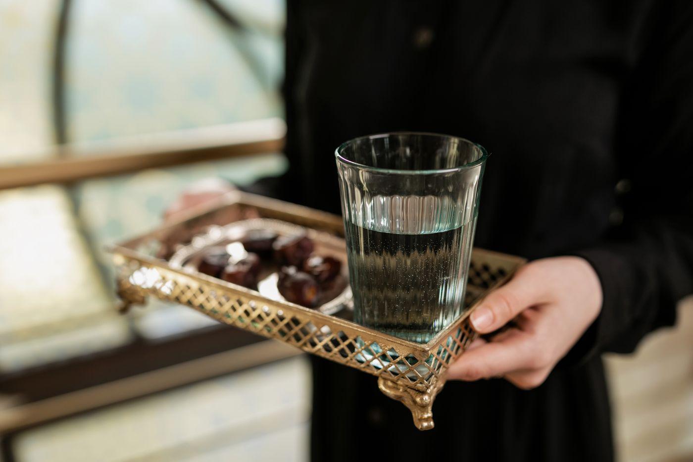 A glass of water and dates on a tray